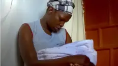 Adama acunando a su bebé, momentos antes de que se suponía que debía venderlo