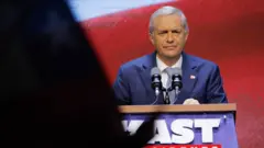 Kast falando ao microfone no púlpito