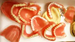 Várias dentaduras em cima de uma mesa