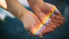 Reflexo de um arco-íris em mãos