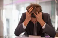 Wani mutum riƙe da kansa a wurin aiki