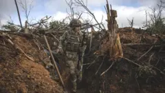 A Ukrainian soldier stands in a trench near Bakhmut, Ukraine