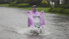 चीनमा झरीमा स्कुटर चलाइँदै