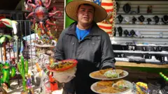 Homem com trajes mexicanos mostra pratos típicos da culinária do país