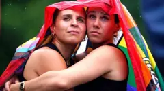 Две девушки обнимают друг друга под радужным флагом 