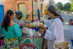 Una vendedora de comida atiende a varios clientes en una calle de México.