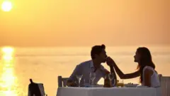 زوجان يستمتعان بعشاء رومانتيكي على الشاطئ