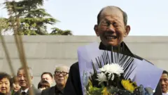 南京大屠殺倖存者佘子清在出席清明節南京大屠殺遇難者悼念儀式時手持菊花痛哭（資料圖片）