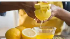 Ọwọ kan n fun n omi ọsan wẹwẹ jade sinu awo. Awọn ọsan naa pọn daadaa, irinṣẹ to n lo paapaa ni awọ pupa bii ọsan wẹwẹ.