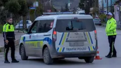 فردان من قوات الأمن التركية يقفان بجوار سيارة شرطة تغلق الشارع أثناء تنفيذ مداهمة أمنية في يالوفا