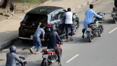 एक गाड़ी को धक्का लगाते कुछ लोग