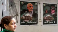 امرأة تمر أمام ملصقات ليحيى السنوار (يسار) في قطاع غزة.