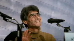 چهره ناصر تقوایی نشسته پشت میز در یک مراسم پرسش و پاسخ