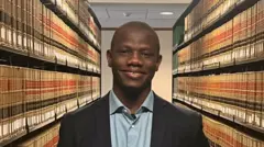 Cheikh Ahmadou Bamba Ndiaye posant au milieu d'une bibliothèque