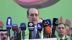 نوری مالکی پشت میکروفون‌های رسانه‌ها در حال صحبت