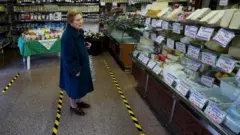 زنی در مغازه خواربار فروشی در رم. خطوط زرد روی زمین برای آن است تا مشتریان فاصله خود را با هم حفظ کنند