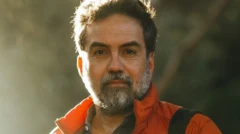 Arturo Bejar, um homem de meia idade com a barba grisalha e olhos castanhos, veste casaco laranja e olha diretamente para a câmera