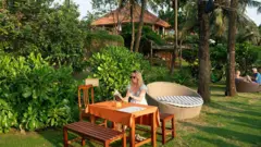Uma turista lê um livro no Cassia Cottage Resort em 20 de março de 2026, em Phu Quoc, Vietnã
