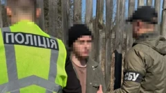 Кадры задержания: полицейский и сотрудник СБУ держат под руки худощавого молодого человека в черной шапке и куртке цвета хаки. Лица у всех заблюрены