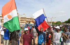 De jeunes manifestants brandissent des drapeaux du Niger et de la Russie 