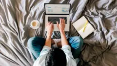 A man works on a laptop on his bed