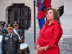Dina Boluarte, vestida de vermelho, em pé.