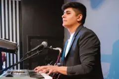 Brasileiro Lucas toca teclado em igreja.