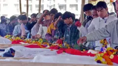 गौर हत्याकाण्डमा ज्यान गुमाएका व्यक्तिहरूका शवपेटिकामा श्रद्धान्जली दिँदै मानिसहरू