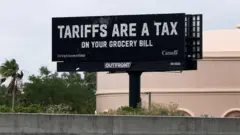 Cartel fotografiado en el sur del estado de Florida que dice, en inglés: "Los aranceles son un impuesto en tu cuenta del supermercado". También muestra el mensaje: "Pagado por el gobierno de Canadá".