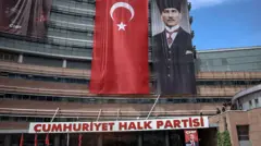 CHP yazan binada Türk bayrağı, Atatürk'ün resmi ve Özgür Özel posteri
