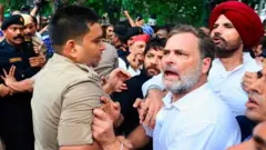 राहुल गांधी को पीएम आवास के बाहर से हिरासत में लेते पुलिसकर्मी