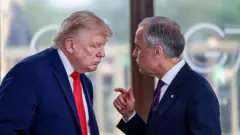 O presidente Donald Trump fala com o primeiro-ministro canadense Mark Carney durante evento do G7