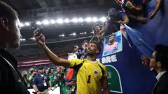 O goleiro cabo-verdiano Vozinha tira uma selfie com torcedores enquanto deixa o campo de jogo em uma partida da Copa do Mundo de 2026