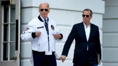 Hunter Biden, son of US President Joe Biden, right, watches as US President Joe Biden gestures to his "Team USA" jacket on the South Lawn of the White House before boarding Marine One in Washington, DC, US, on Friday, July 26, 2024. 