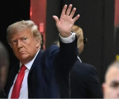 Donald Trump fait un signe de la main pour saluer quelqu'un ou une foule qui est hors champ