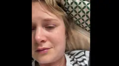 Beth Parsons tem cabelos louros, veste camiseta listrada e aparenta estar indisposta e cansada