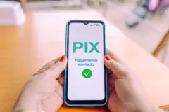 Pessoa segurando celular. Na tela, mensagem: 'Pix - Pagamento enviado'