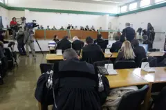 Pessoas reunidas em uma sala durante um julgamento