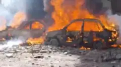 日中の道路で複数の車両が燃え、周りにがれきが散らばっている