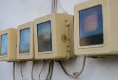 Four analog electricity meters in a row on the outside of a building close up shot.