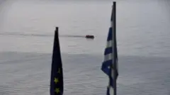 عکس پرچم یونان و اتحادیه اروپا با پس زمینه قایق حامل مهاجران در دریا