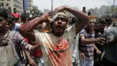 පසුගිය සතියේ ඩකාහි තුවාල ලැබූ විරෝධතාකරුවෙක් - ආරක්ෂක හමුදාවන්ගේ වෙඩි ප්‍රහාරවලට ලක් වූ පුද්ගලයින්ට ප්‍රතිකාර කිරීමට රෝහල් අසීරු කාර්යයක නිරත විය