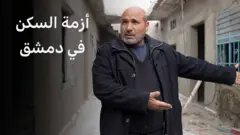 صورة رجل سوري أمام منزله المهدم