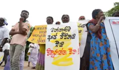 මන්නාරම සුළං විදුලි බලාගාරයට එරෙහිව විරෝධතා අතැතිව විරෝධතා දක්වන පිරිසක්. එහි ඉදිරියෙන් සිටින කාන්තාවක අත ඇති විරෝධතා පුවරුවේ සුදු මිශ්‍ර කහ පැහැති පසුබිමක කළු පැහැයෙන් මෙසේ ලියා ඇත: "මන්නාරම අපේ ජීවිතය". ඊට පහළින් රතු පැහැයෙන් මෙසේ ලියා ඇත: "එය විකුණන්න එපා!"