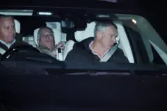 Imagem mostra Andrew reclinado no banco de trás de um carro. Há um homem dirigindo o veículo e outro no banco do passageiro