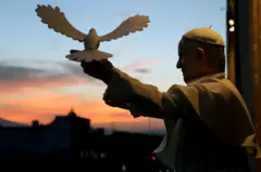 Papa Francisco de costas posando com uma réplica de pomba da paz durante visita ao México