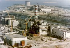 Vista da Usina Nuclear de Chernobyl em 29 de abril de 1986, três dias após a explosão. O prédio que abriga o reator quatro está gravemente danificado, com destroços enegrecidos abaixo de uma chaminé vermelha e branca
