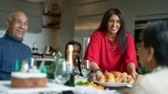 Smiling woman serving roasted turkey to family at table