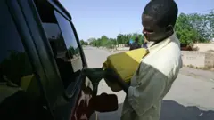 One black man dey use jerrycan put fuel inside one car