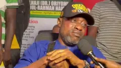 Surii Ilupeju wọ aṣọ olomi aro, gbohungbohun wa niwaju rẹ